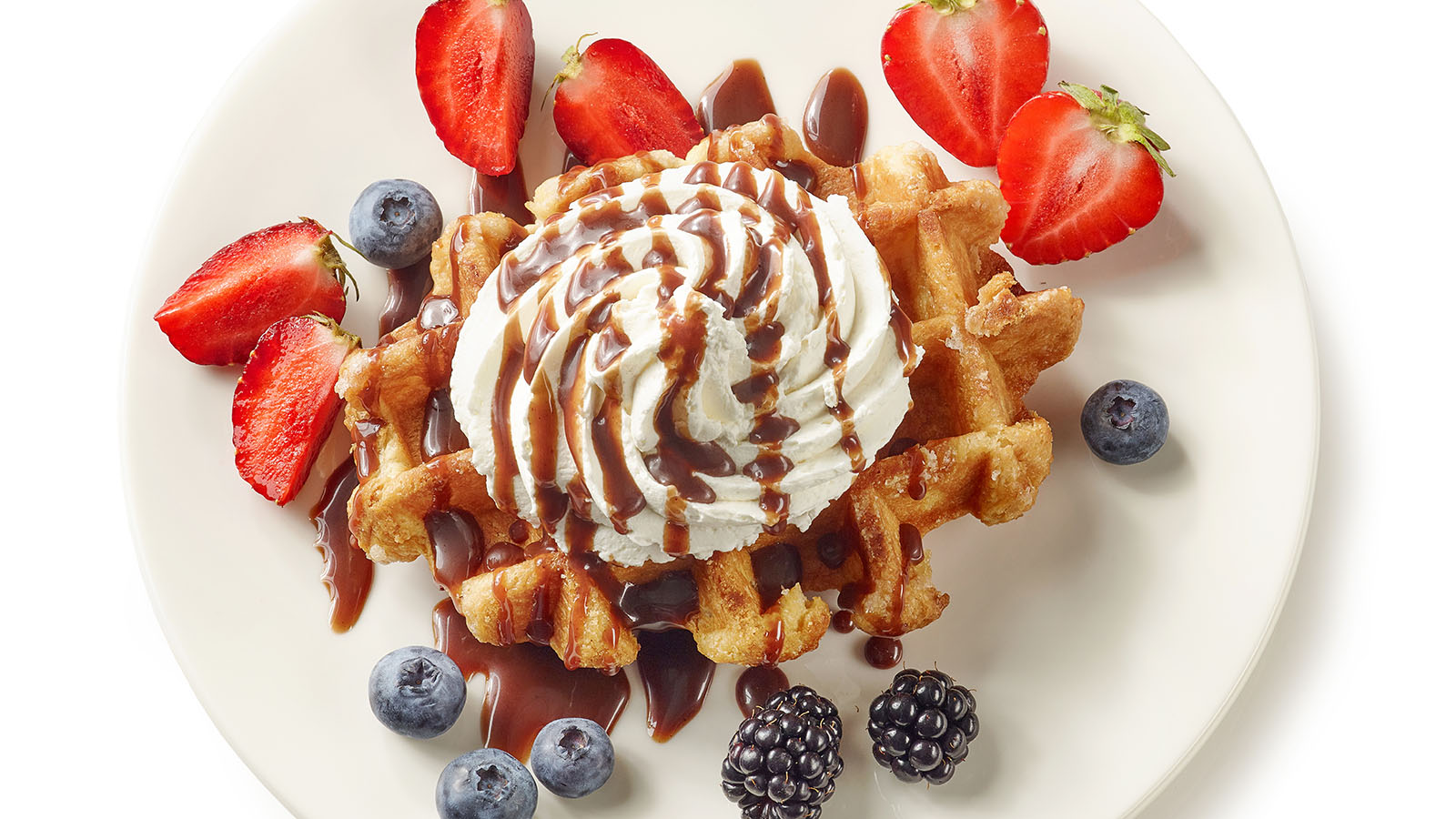 Crispy hot waffles topped with fresh sliced sweet strawberries and a mound of whipped cream.