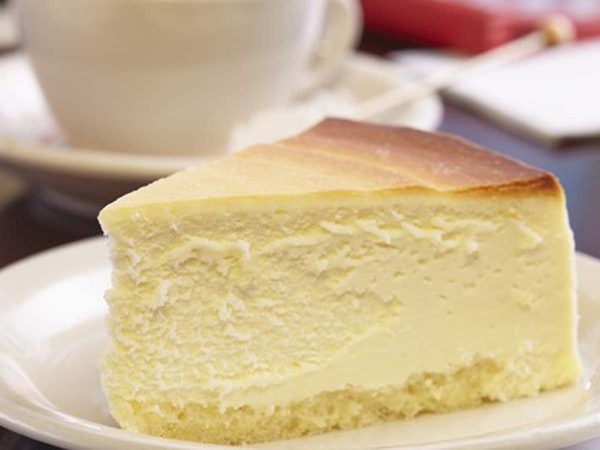 A dense, rich slice of authentic baked New York cheesecake on a plate.